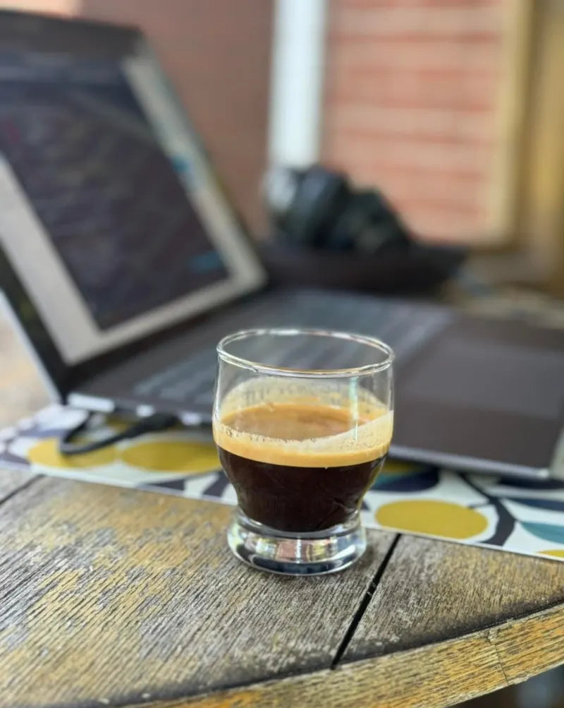 A short glass of espresso on a weathered wooden table